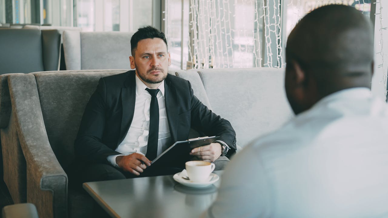 about-us Two businessmen having a serious conversation over coffee in a stylish cafe setting.